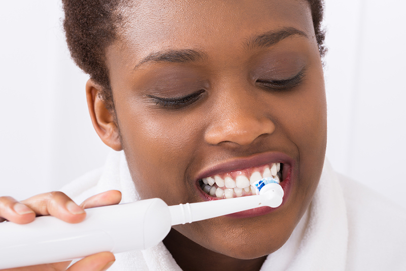 Close-up Of A Young African Woman Brushing Teeth With Electric Toothbrush