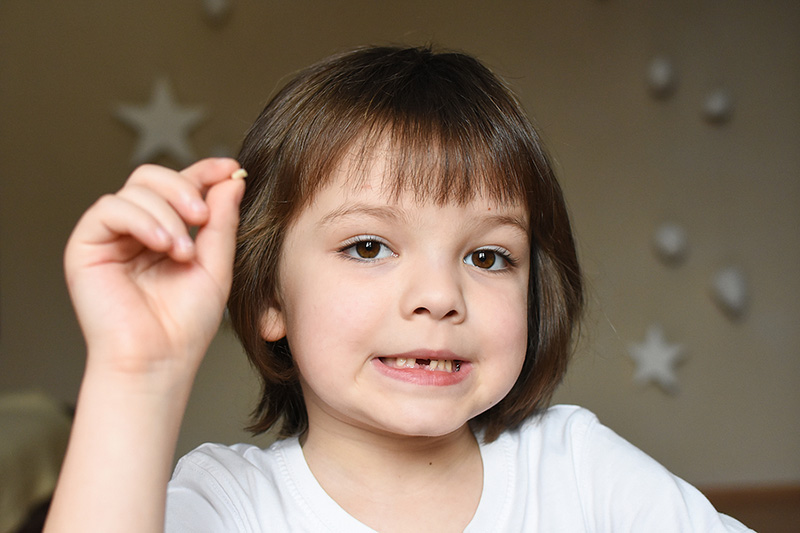 Little boy smiling and showing off a lost tooth.