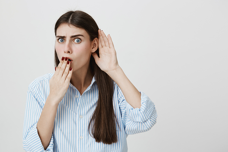 woman covering mouth and cupping ear