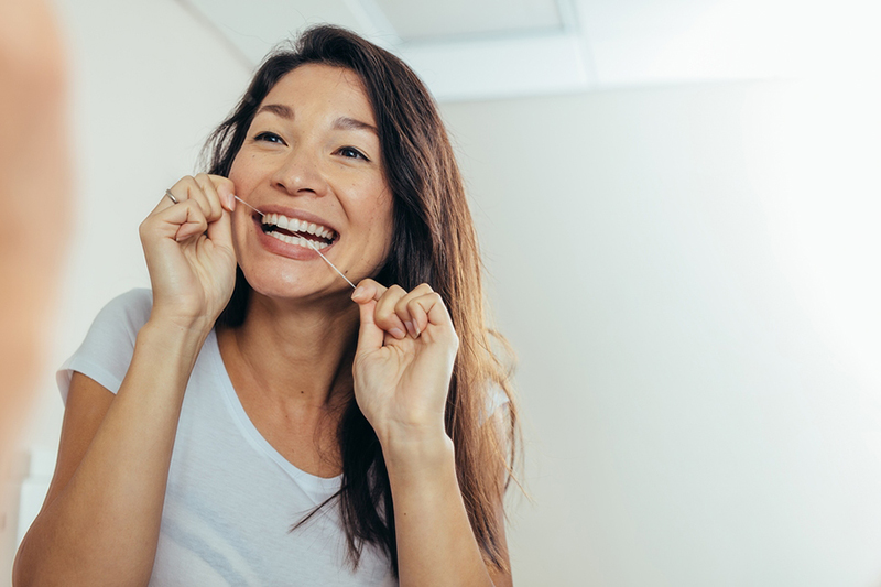 Woman flossing and smiling